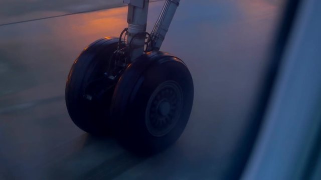 Plane wheel taxiing on airport tarmac at night. 