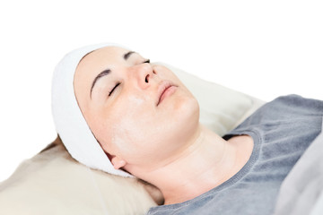 Fototapeta na wymiar Young woman lying with a cosmetic cream on her face. Cosmetology. Beauty procedure. Facial skincare