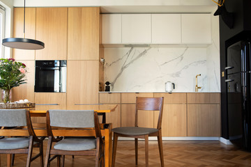 Modern scandinavian open space interior of kitchen with design furniture, black fridge, marble...