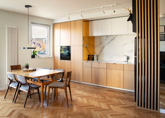 Stylish and cozy scandinavian dining room and kitchen with design family table, chairs and lamp....