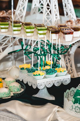 Fototapeta premium green style wedding candy bar on a white table. cupcakes decorated with a green ribbon bow