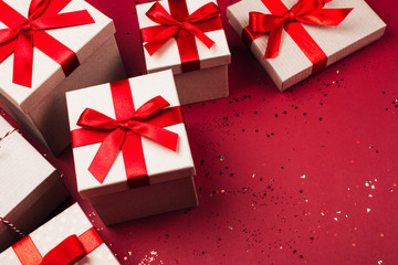 Many present boxes with red bow on red background. Flat lay style.