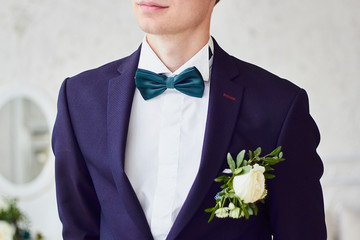Close-up the young fiance in jacket on with boutonniere of white rose.