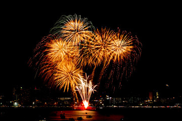 Many flashing fireworks with night cityscape background celebrate New Year.