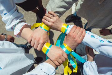 people are dressed in traditional Ukrainian clothes holding their hands together, success unification of the nation concept