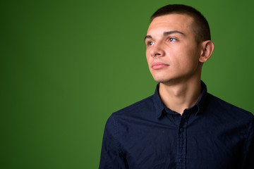 Studio shot of young handsome businessman against green backgrou