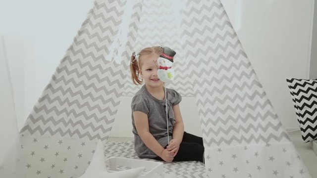 Very beautiful and little girl playing in a tepee.