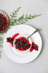Homemade Cranberry Sauce on White Plate with Cedar Sprigs on a Light Gray Background