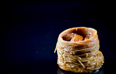 Middle Eastern dessert called mabroume or burma isolated on black background.