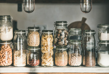 Rustic kitchen food storage arrangement. Grains, cereals, nut, dry fruit, flour, pasta kinds in...