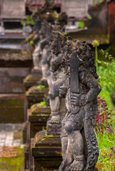 Fototapeta na wymiar Balinese Stone Statuary at the Hindu Temple. Ancient stone carvings depicting the battle between good and evil meant to protect the temple and the worshipers.