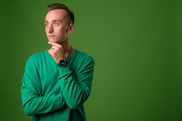 Studio shot of young handsome man against green background
