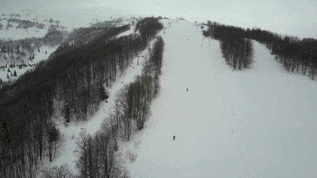 Carpathian ski resort from a height. Flight over mountains. Bird's eye view of people descending on skis.