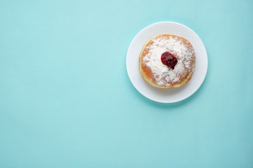 Tradition Jewish holiday sweets, donut sufganioyt with sugar powder and jam on blue background top...