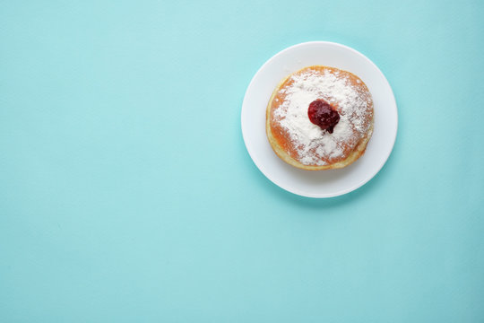 Tradition Jewish holiday sweets, donut sufganioyt with sugar powder and jam on blue background top view with copy space