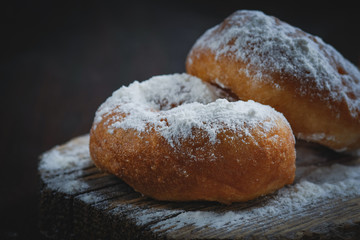 Tradition Jewish holiday sweets, donut sufganioyt with sugar powder on dark background