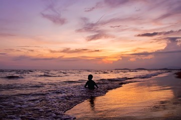 Silhouette of boy playing on the beach at sunset