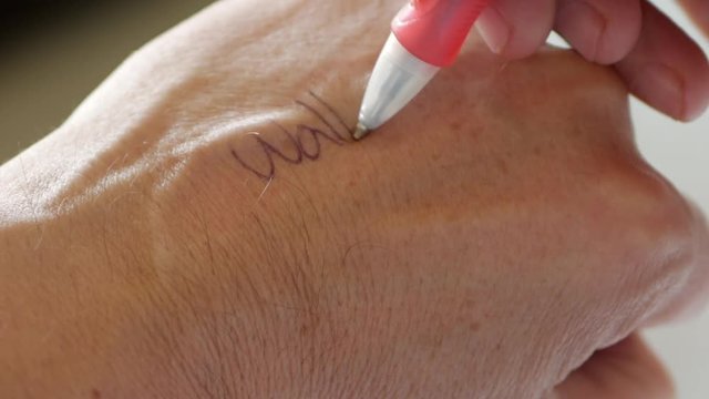 Man writes a note on the back of his hand. Reminder note to do a task.