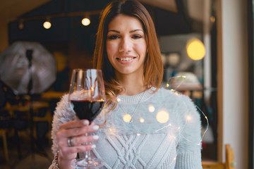 young woman in a restaurant holding a glass of red wine