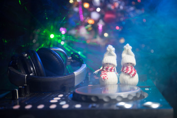 Dj mixer with headphones on dark nightclub background with Christmas tree New Year Eve. Close up...