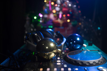 Fototapeta na wymiar Dj mixer with headphones on dark nightclub background with Christmas tree New Year Eve. Close up view of New Year elements on a Dj table. Holiday party concept.