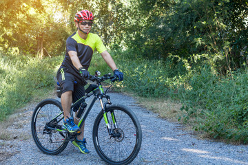 Fototapeta premium Man with helmet glove for safety riding a bicycle at countryside road along a forest,Cross country riding,cycling activity and sports.