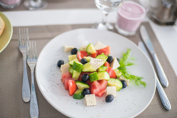 Greek salad of fresh cucumber, tomato, sweet pepper, lettuce, red onion, feta cheese and olives with olive oil. Healthy food, top view
