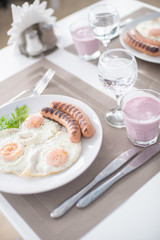 Traditional breakfast with  sausages, fried eggs, bread and yogurt
