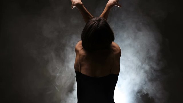 modern ballet dancer posing on dark background with smoke