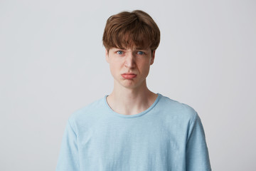Portrait of blue-eyed young guy looks sad, upset, frustrated, displeased with the result of the...