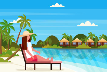 woman sitting sun bed lounge chair on tropical island villa bungalow hotel beach seaside green palms landscape summer vacation concept flat horizontal