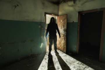 Serial killer maniac with knife in dark abandoned building. Maniac thriller concept - obrazy, fototapety, plakaty