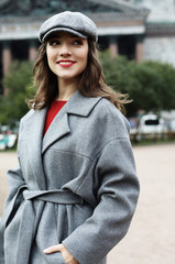 Lifestyle and people concept: Close-up portrait of young woman in elegant gray coat standing on the street in autumn day.