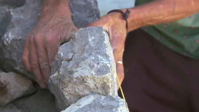 Manual stone wall construction. Building a stone house. The hands of a man while building the stone wall