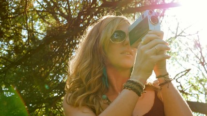 Groovy woman filming with 8mm movie camera. Sunny with lensflare.
