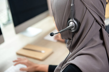 Back view of muslim woman customer service staff wearing microphone headset working in call center office