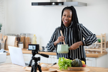 African american woman cooking vlogger recording video in kitchen at home