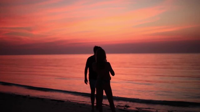 Silhouette of couple taking photo on beach during amazing sunset. hd