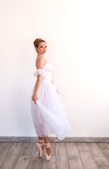 Fototapeta na wymiar Young graceful ballerina dancing on white studio.
