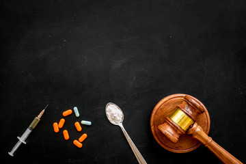 Drugs addiction, arrest for drugs. Pills, spoon with powder, syringe on black background top view copy space