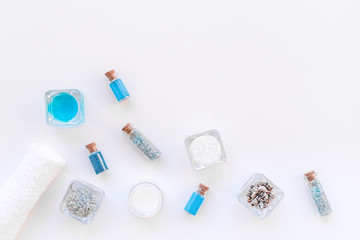 Sea salt for spa and aroma spa cosmetics near towel and shells on white background top view copy space