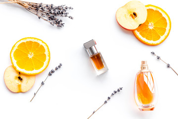 Sweet perfume with fruit fragrance. Bottle  of perfume near apple, orange, lavender on white background top view