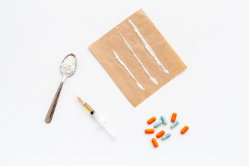 Take drugs, drugs addiction concept. White powder like heroine or cocaine, drug tracks pills, spoon, syringe on white background top view copy space