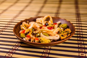 Ceramic plate with different sea food and olives on a bamboo mat