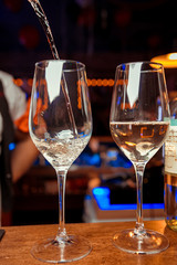 Pouring white wine into glasses in the vineyard, toned