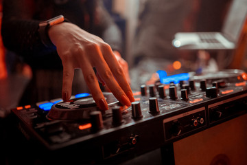 Blurred background with dj girl playing music and scratching tracks on professional dj midi...