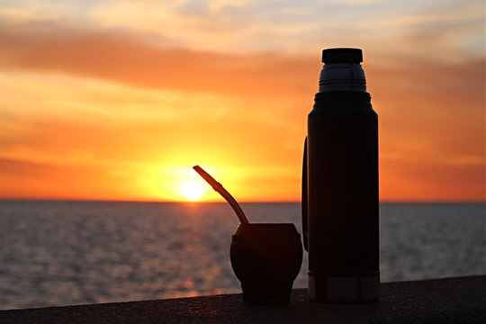 Silueta de mate con garrafa t&eacute;rmica apoiada na mureta da Rambla no por do sol as margens do Rio da Prata