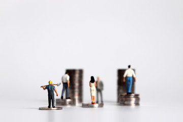 Miniature people with piles of coins. The concept of economic inequality between employers and...