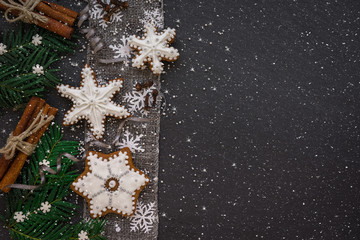 Frame with fir branches, Gingerbread cookies, spices and Christmas decorations on dark stone background. Top view.