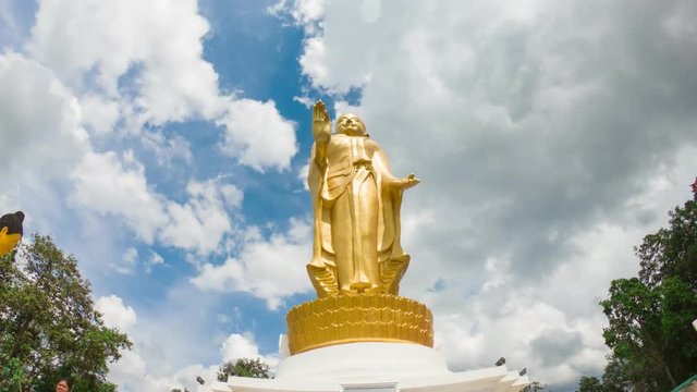 Bronze statue of Buddha standing in a modern city centered at timelapse.